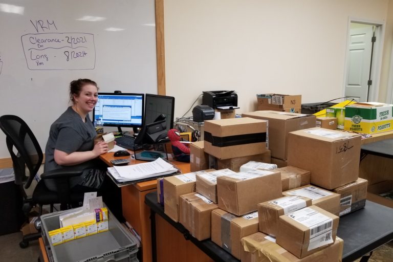 Photograph of young woman working at computer and checking in diabetic test strips