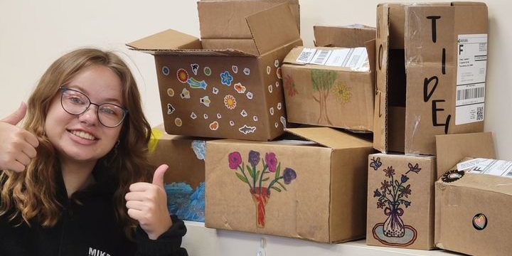 Sell Diabetic Strips and Have Fun! Young Girl with thumbs up near decorated shipping boxes