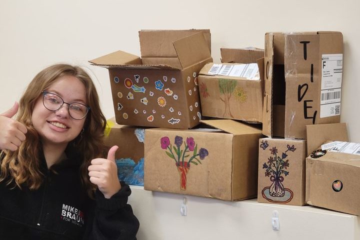 Young Girl with thumbs up near decorated shipping boxes