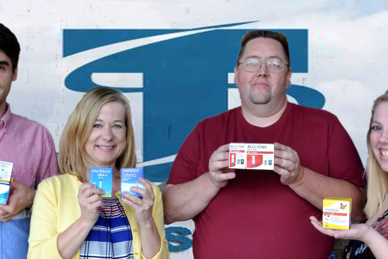 Four people holding boxes of diabetic test strips in front of logo